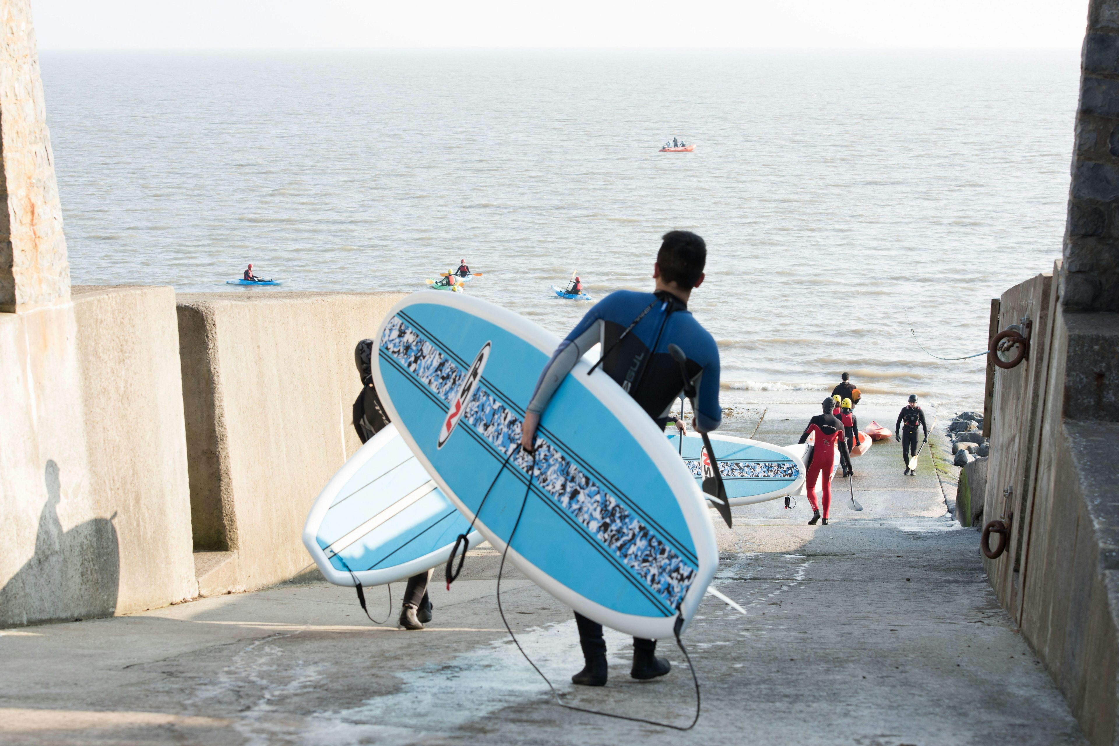 A surfer with a light-blue surfboard is walking towards the sea